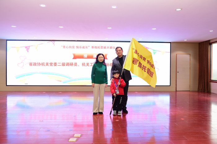 省政协机关党委二级调研员、机关工会主席孙晓辉为托管班小班授旗，请家长省科协机关党委主任科员晏瑜和晏恺骏小朋友上来代表托管班小班接旗.JPG
