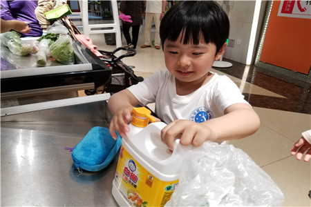 小朋友细心地为妈妈挑选了一瓶洗洁精.jpg