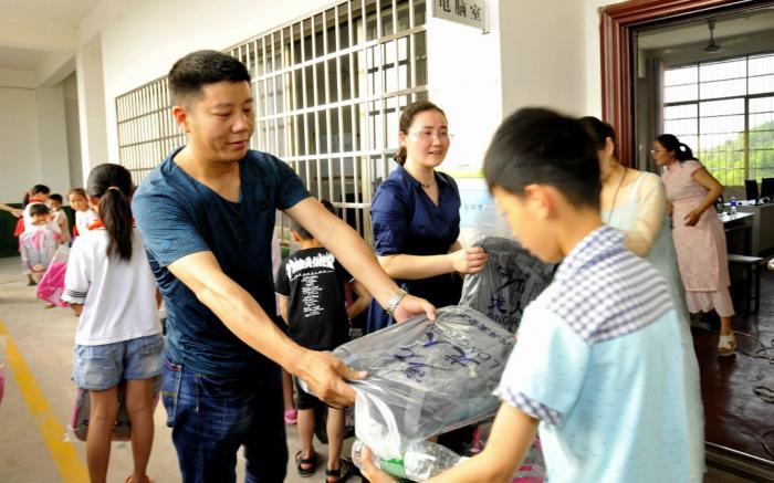 工作人员为孩子们发放学习包，孩子们脸上荡漾着幸福的微笑。.jpg